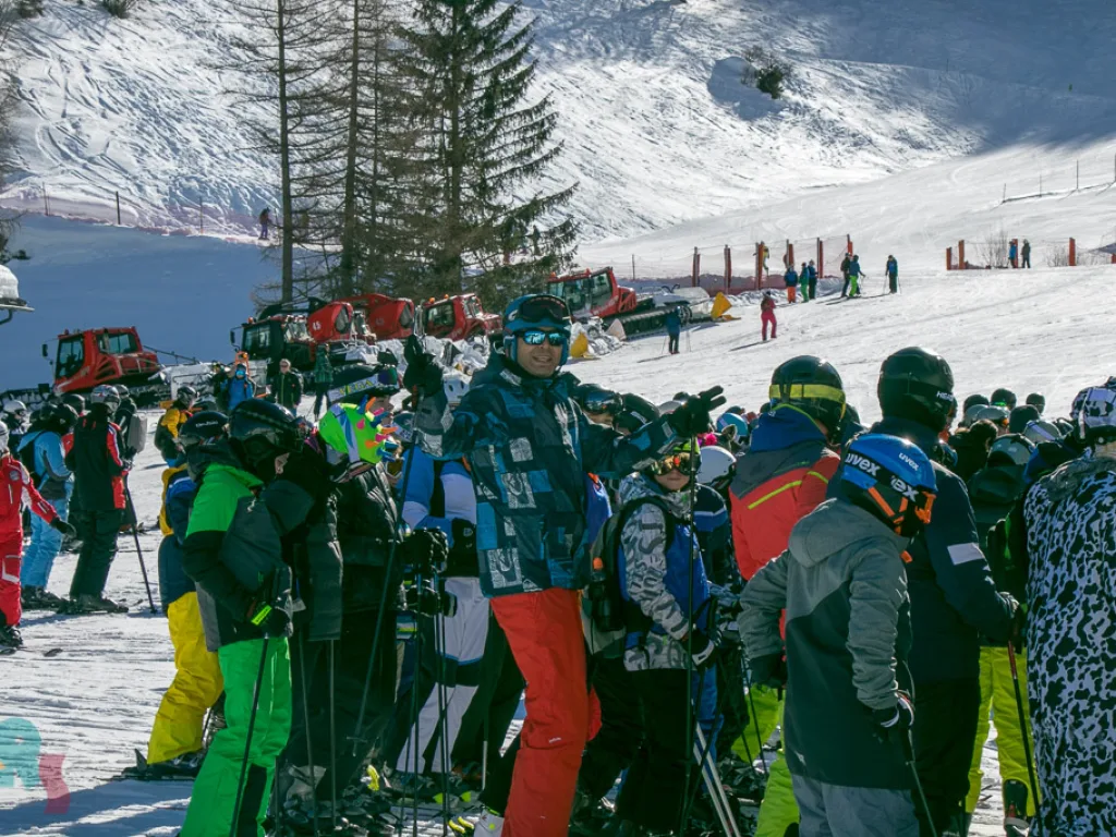 Belebte Talstation mit vielen Skifahrenden.